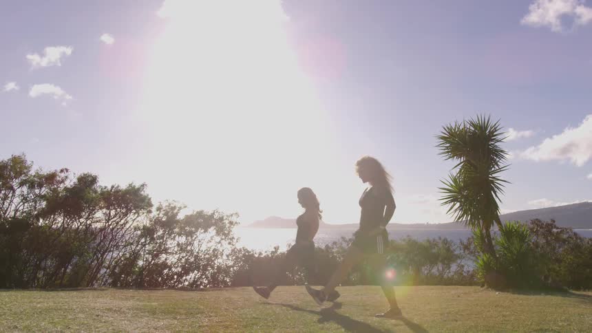 Two women are exercising outdoors in the sun