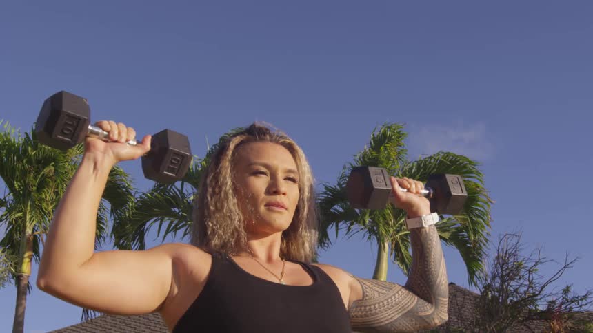 A woman is lifting weights outdoors