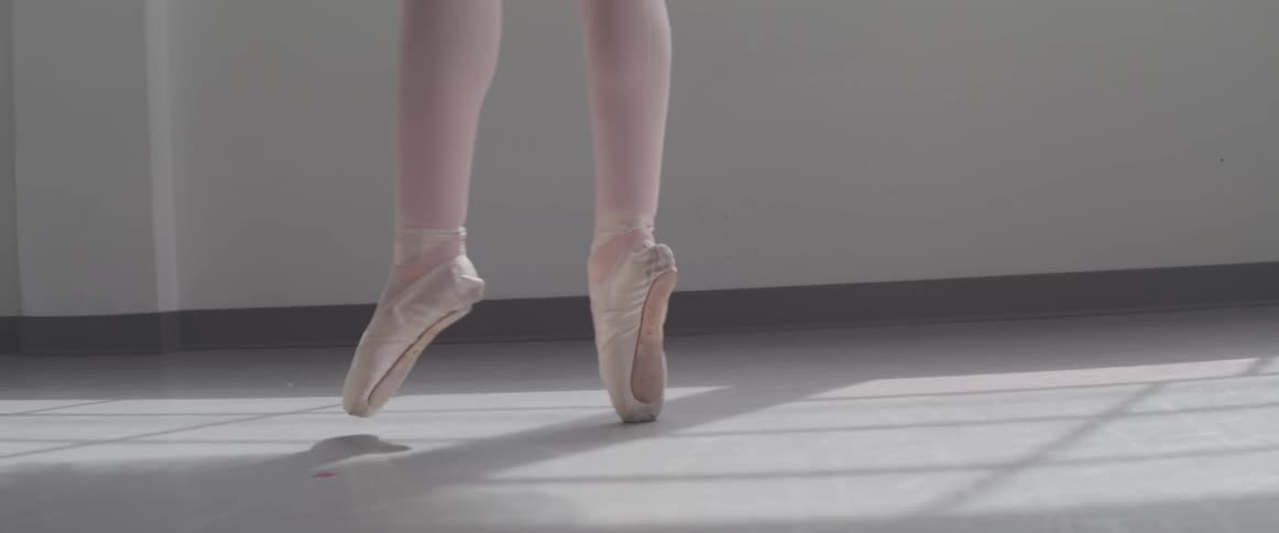 A ballerina dances en pointe wearing ballet slippers