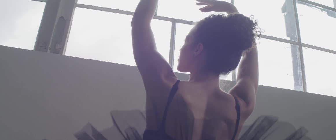 Ballet dancer wearing black ballet costumes dances indoors during daylight