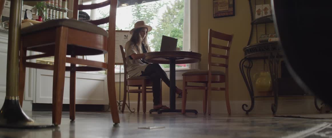 A woman works on her laptop at the kitchen table
