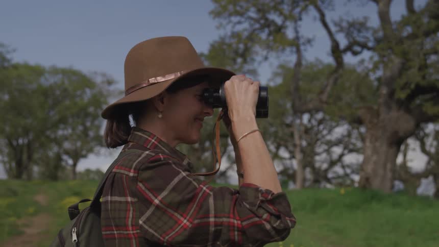 A woman is looking while holding binoculars