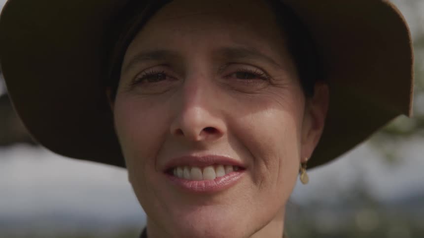 A woman is smiling while wearing a hat