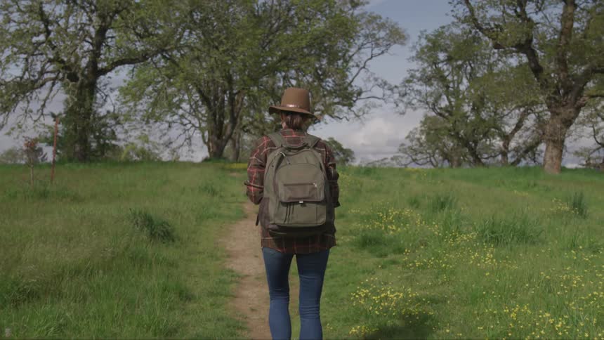 Person hikes through grass with a backpack