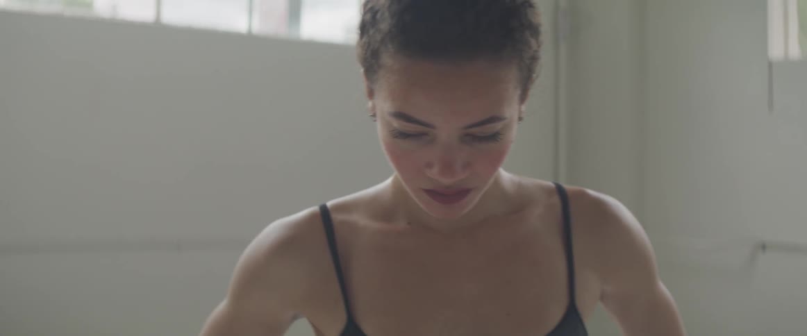 A woman stands in a room and looks at the camera