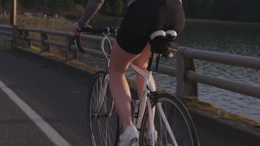 A woman riding a bicycle down a roadway next to a river