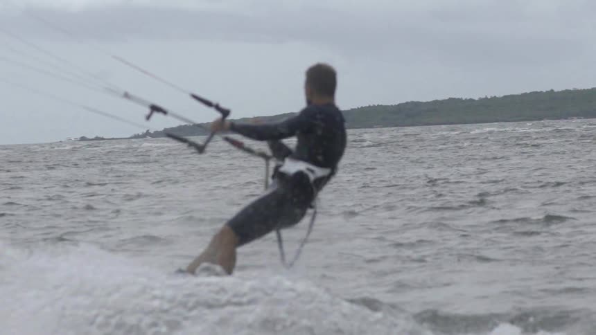 A man is parasailing in the water on a cloudy day