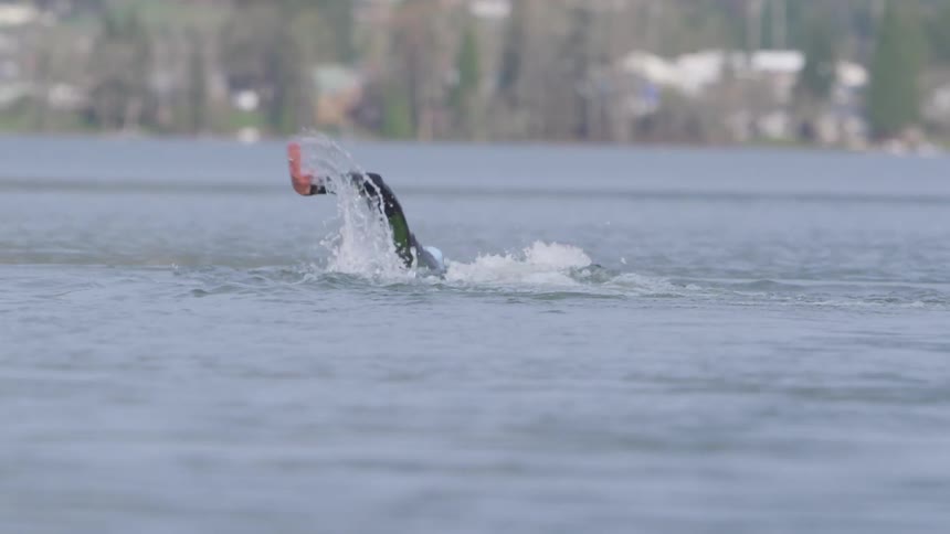 A man is swimming across a large lake in the daytime