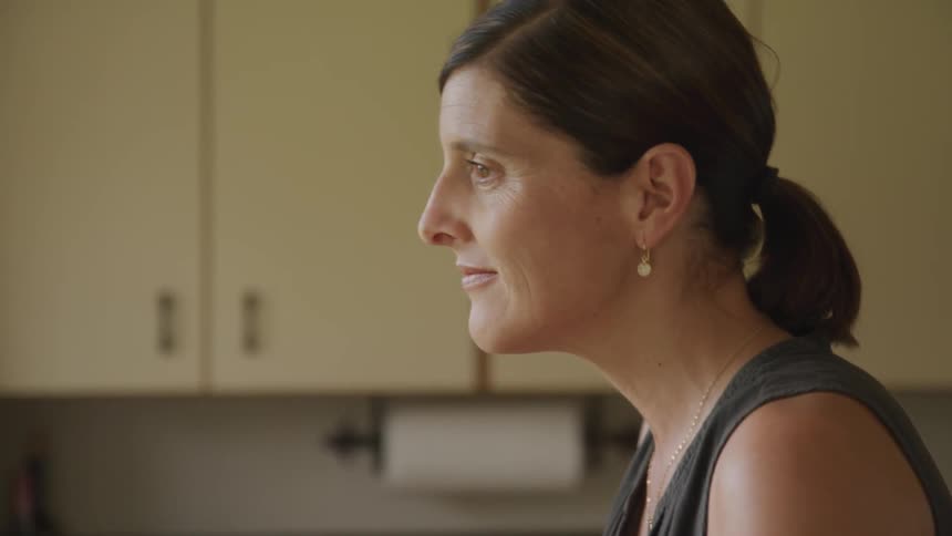 A woman smiling while standing in a kitchen