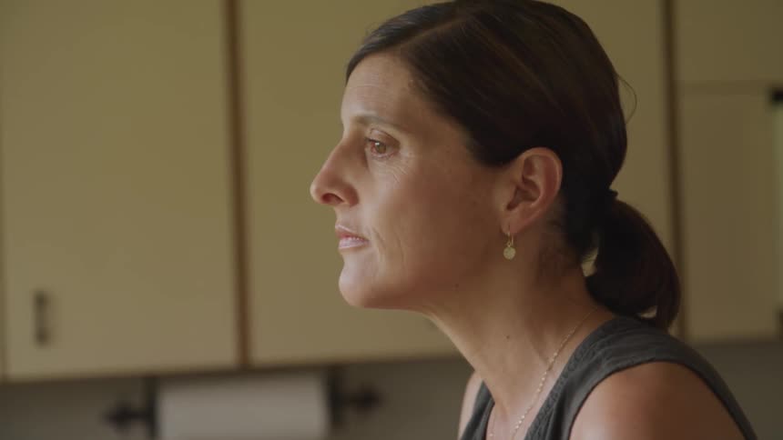 A middle aged woman contemplatively thinking at the kitchen