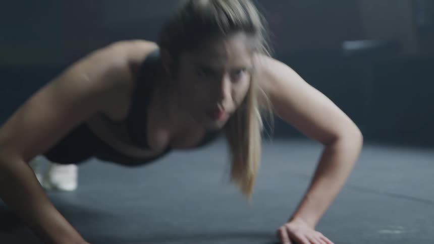 Blonde woman does push ups in the gym indoors
