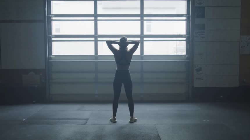 Woman stands shifting left and right before windows