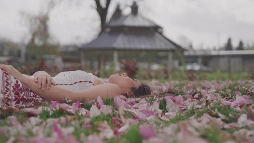 A woman lays in a field of flower petals