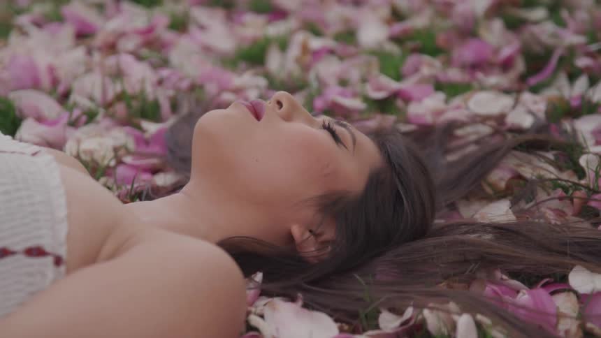 A woman laying in grass and flower petals