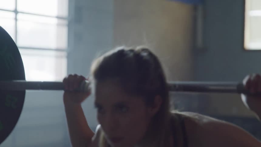 A young woman preparing to lift barbells in a gym