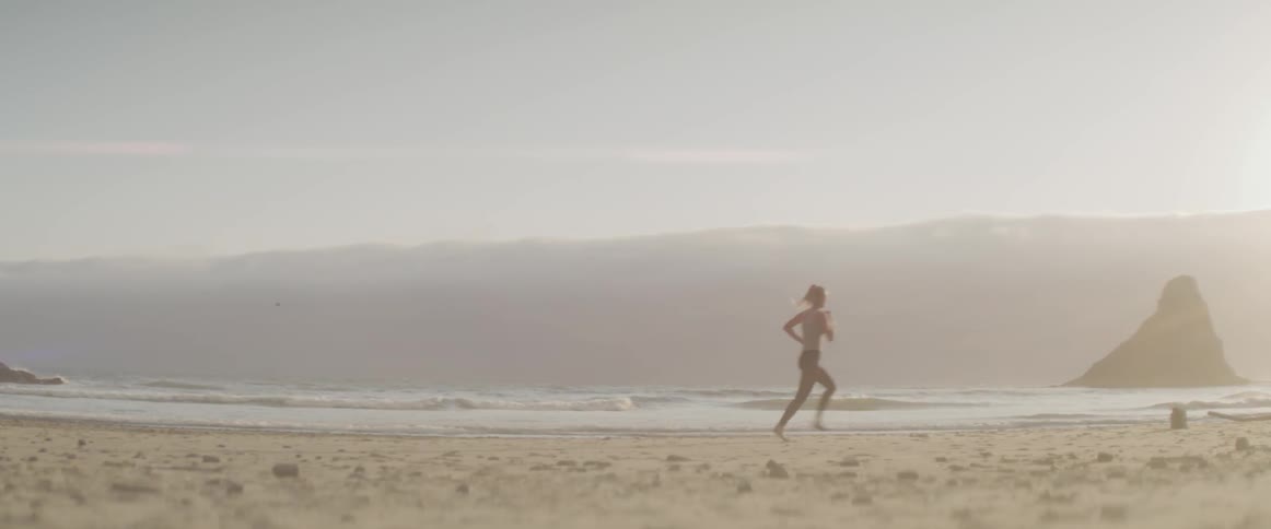 A woman is jogging by the beach