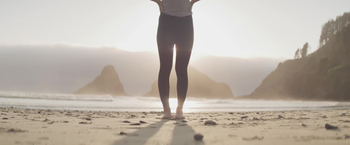 Female standing on shoreline with beach behind her