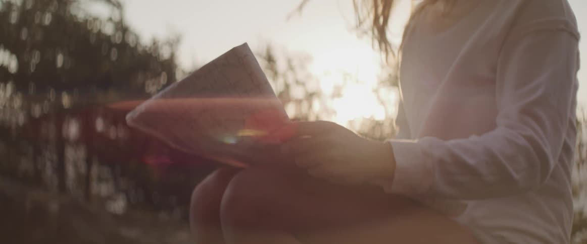A female analyzes a piece of paper outside on a nice day