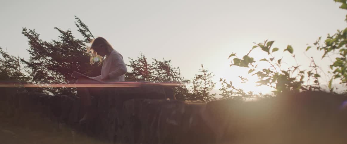 A woman sits on rock edge