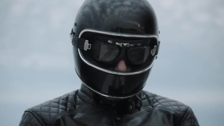 A man wearing a helmet goggles and leather jacket