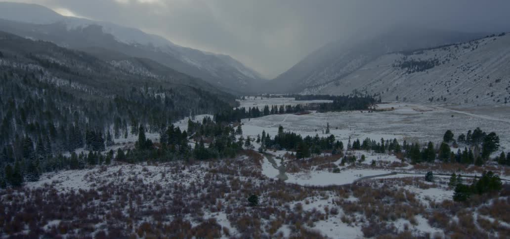 An aerial view of a snowy mountain forest and lake