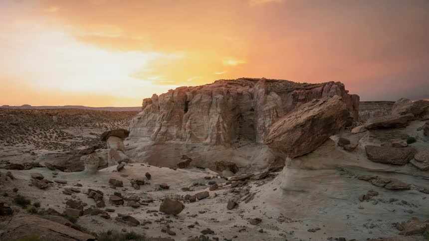 A scenery of a big rock in a canyon at sunset