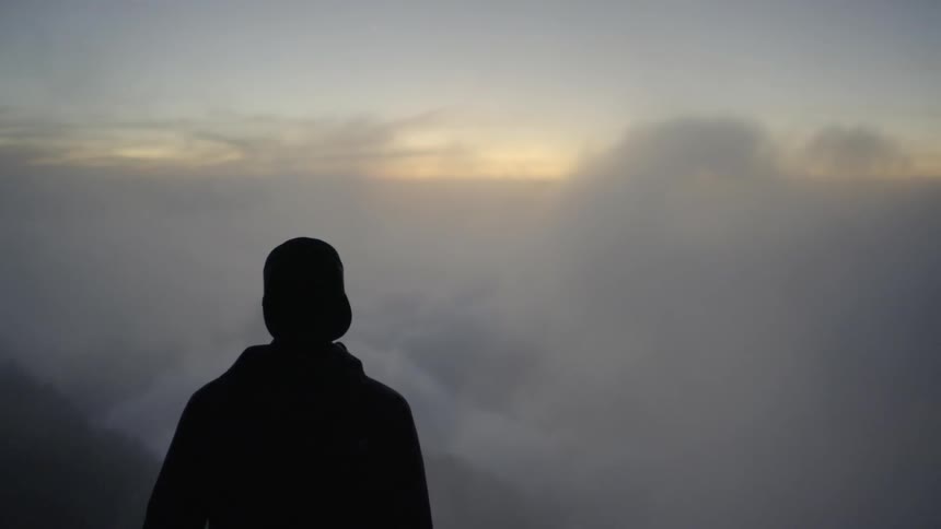 A man is standing outside looking at the clouds