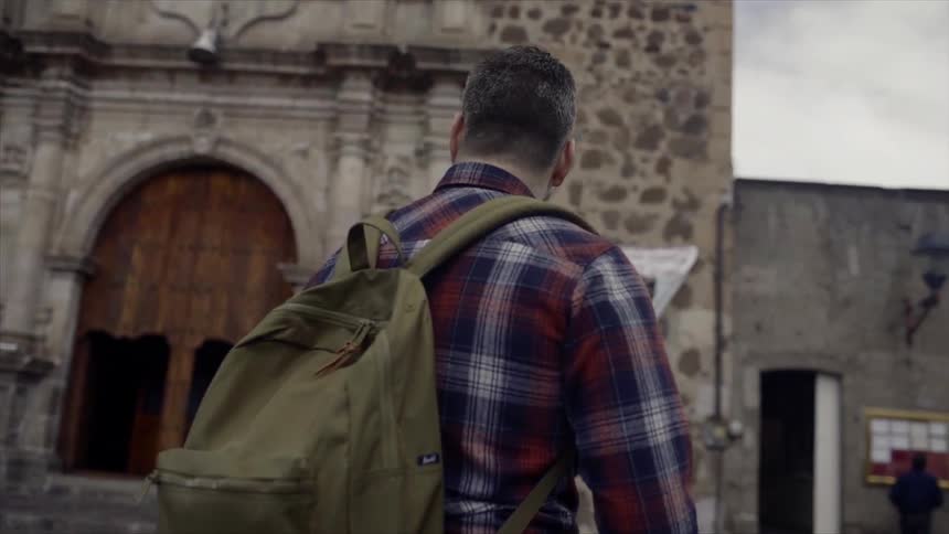 A man walks through an old town with a backpack