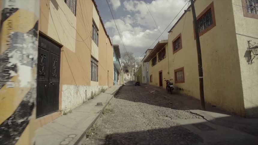 A motorcycle parked in an alley in a run down neighborhood
