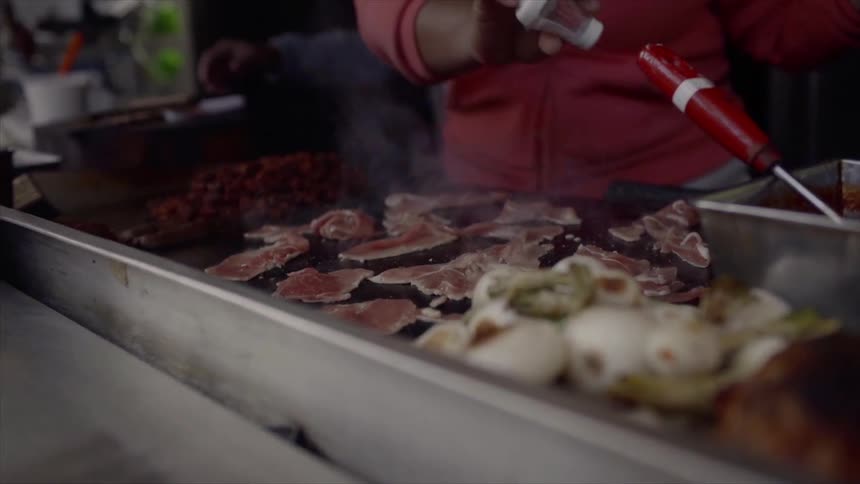 Woman seasons meat on indoor grill