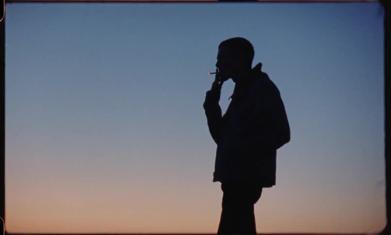 Silhouette of a man standing outside smoking