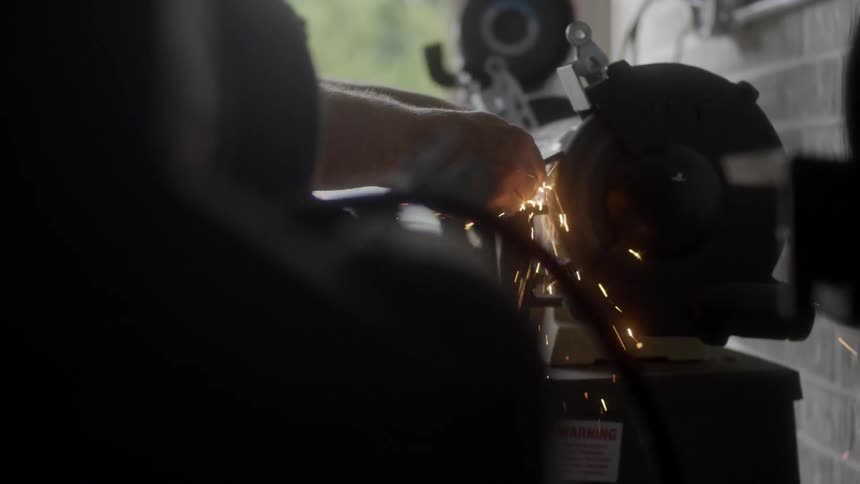 Man grinding something on the grinder at the workshop