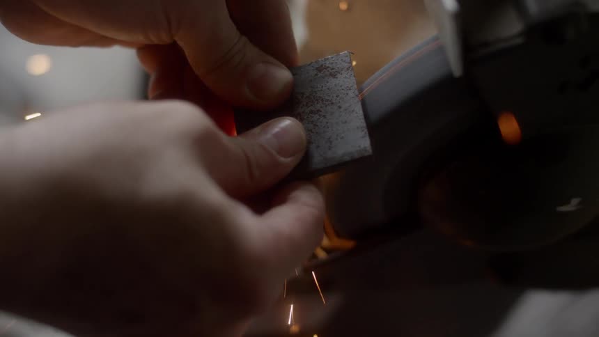 Man grinding an object on the grinder with his hand