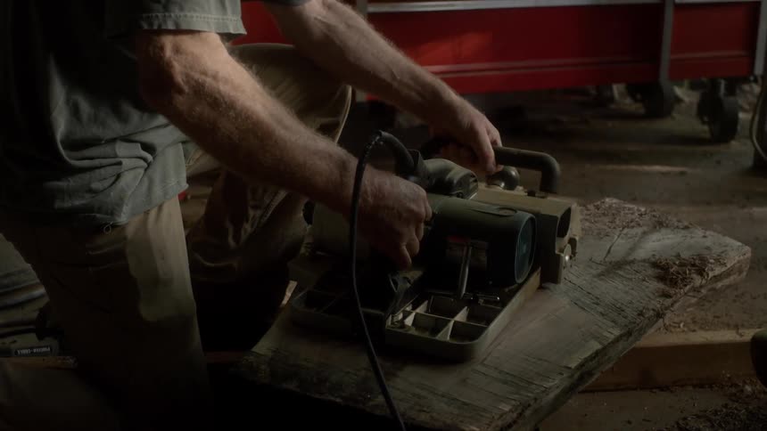 Man grinding wood plank with machine at the workshop