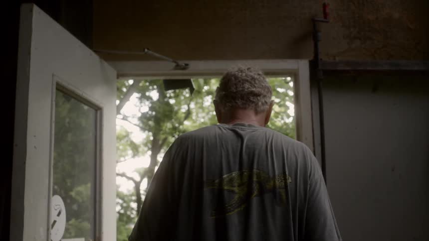 An elderly man walking outside from the house