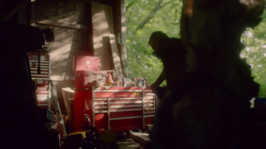 A man uses tools in a cluttered garage