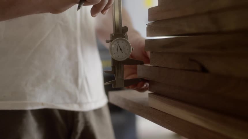 A person uses a tool to measure the thickness of a piece of wood