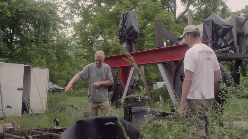 2 man walking through machinery wreckage