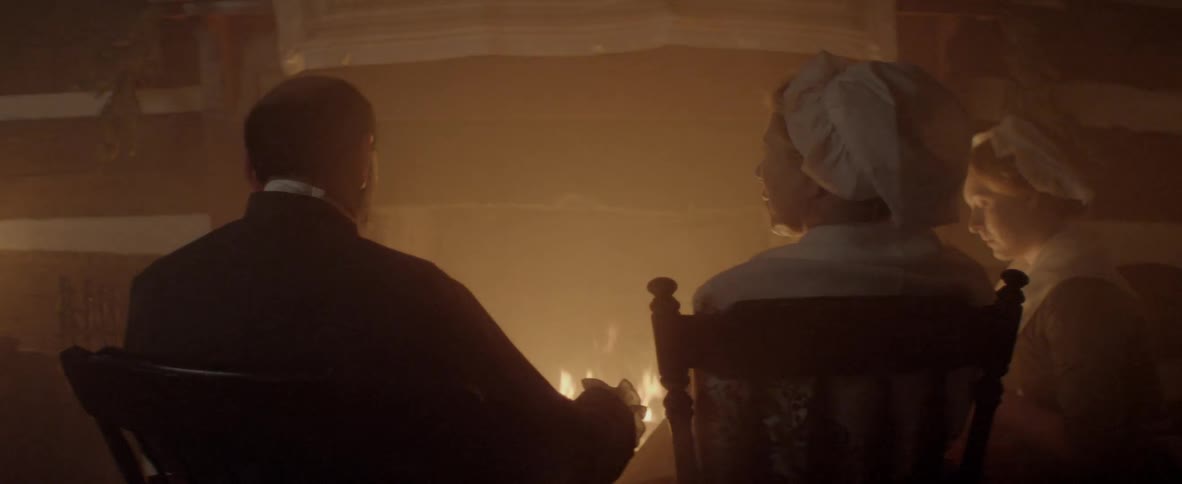 Three people sitting around a fire
