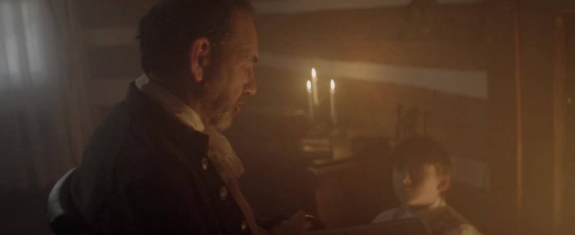 Father and son discussing about something at the living room under the candle light at night