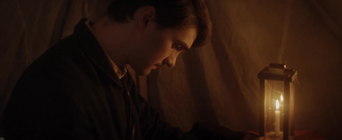 Man in tent writing using candle light