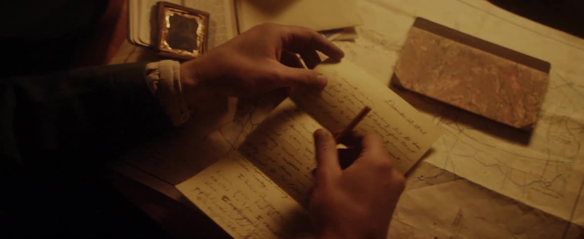 A person writes a letter at a desk and folds it up