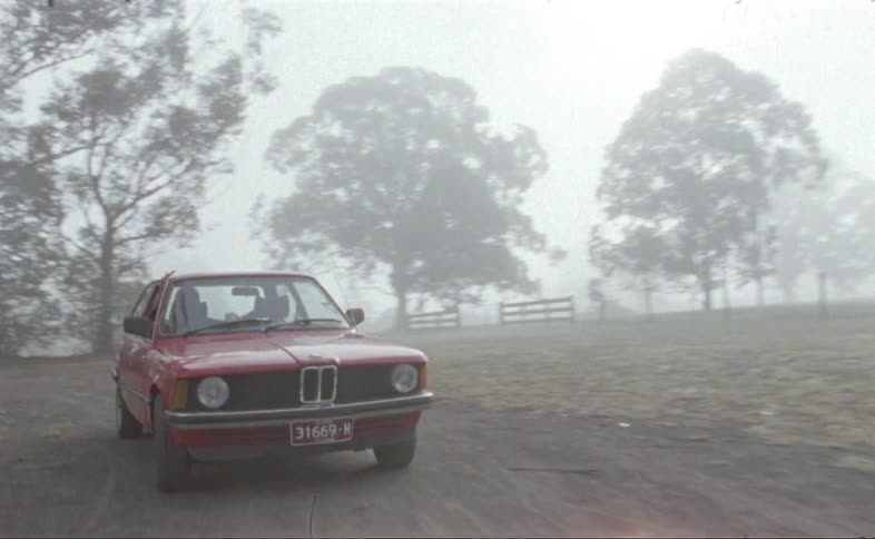 A classic bmw three series is driven on a dirt road