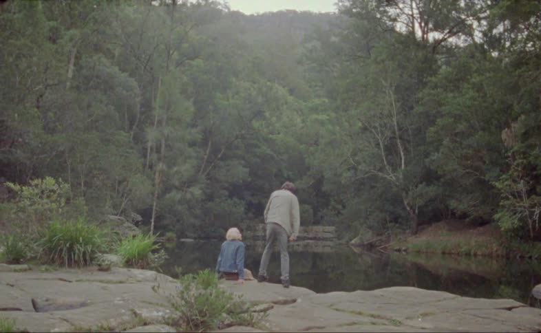 A couple sit down together by the water