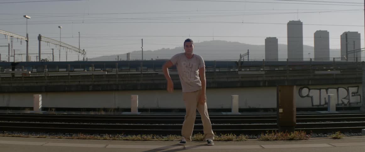 A man happily dances the robot in front of train tracks