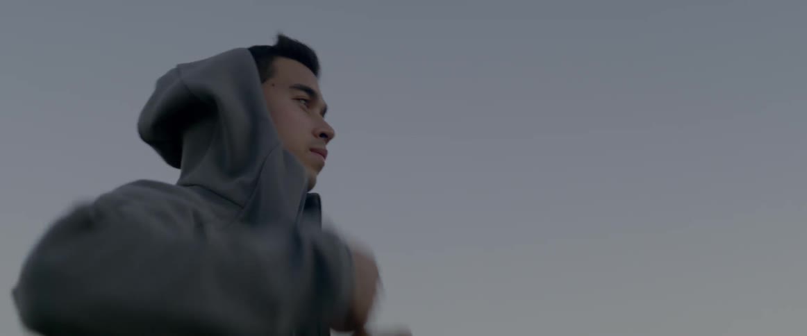 A young man pulls up his hood on his hoody