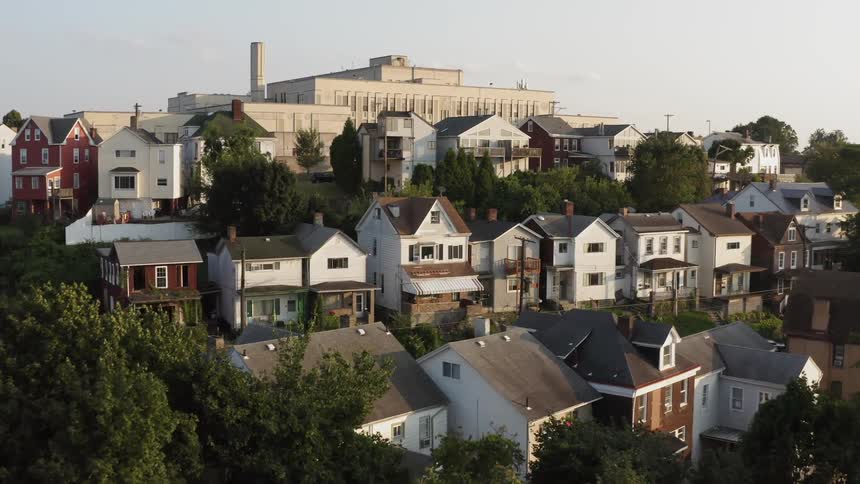 A factory looms over rows of homes in a neighborhood