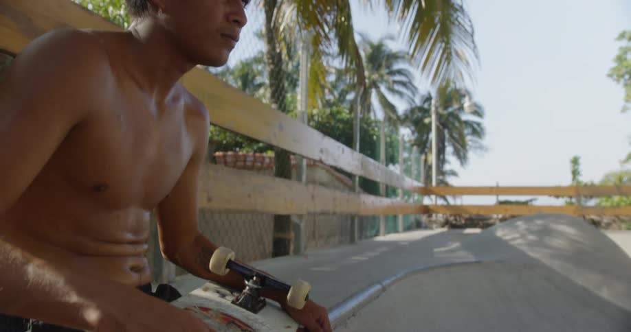 A man sits on a ledge holding a skateboard