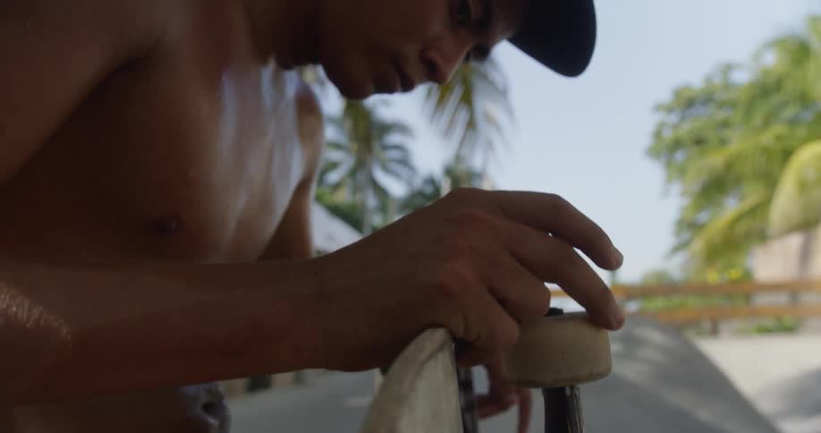 A close up shot of a man holding onto his skateboard outside
