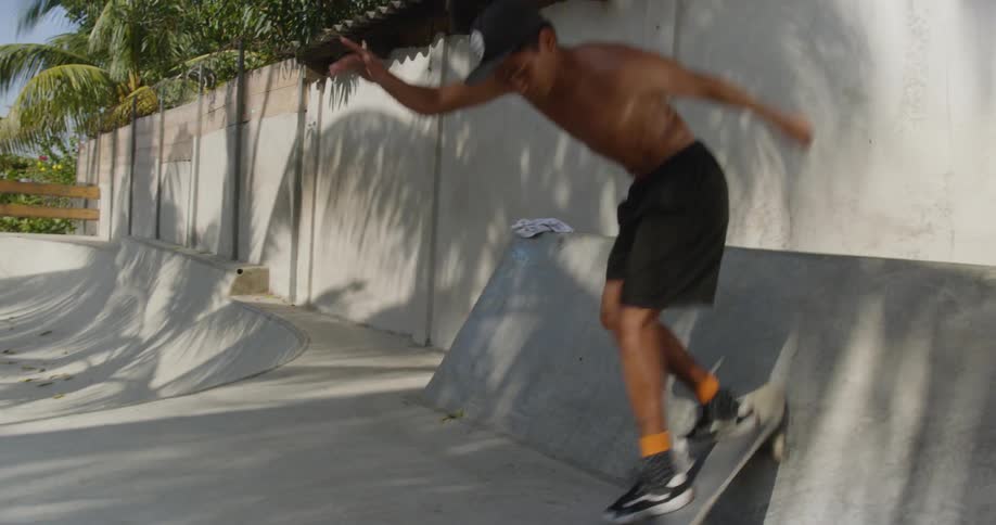 A hispanic teen attempts to do a trick on a skateboard